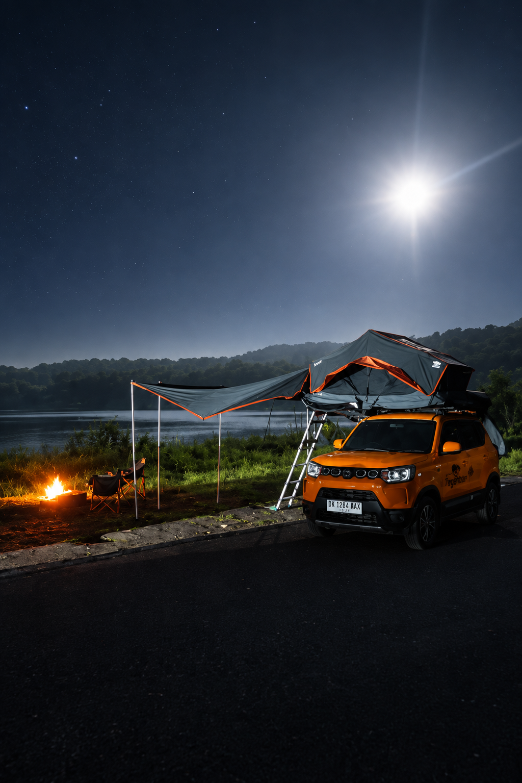 Camp set up by a lake at night with a fire going