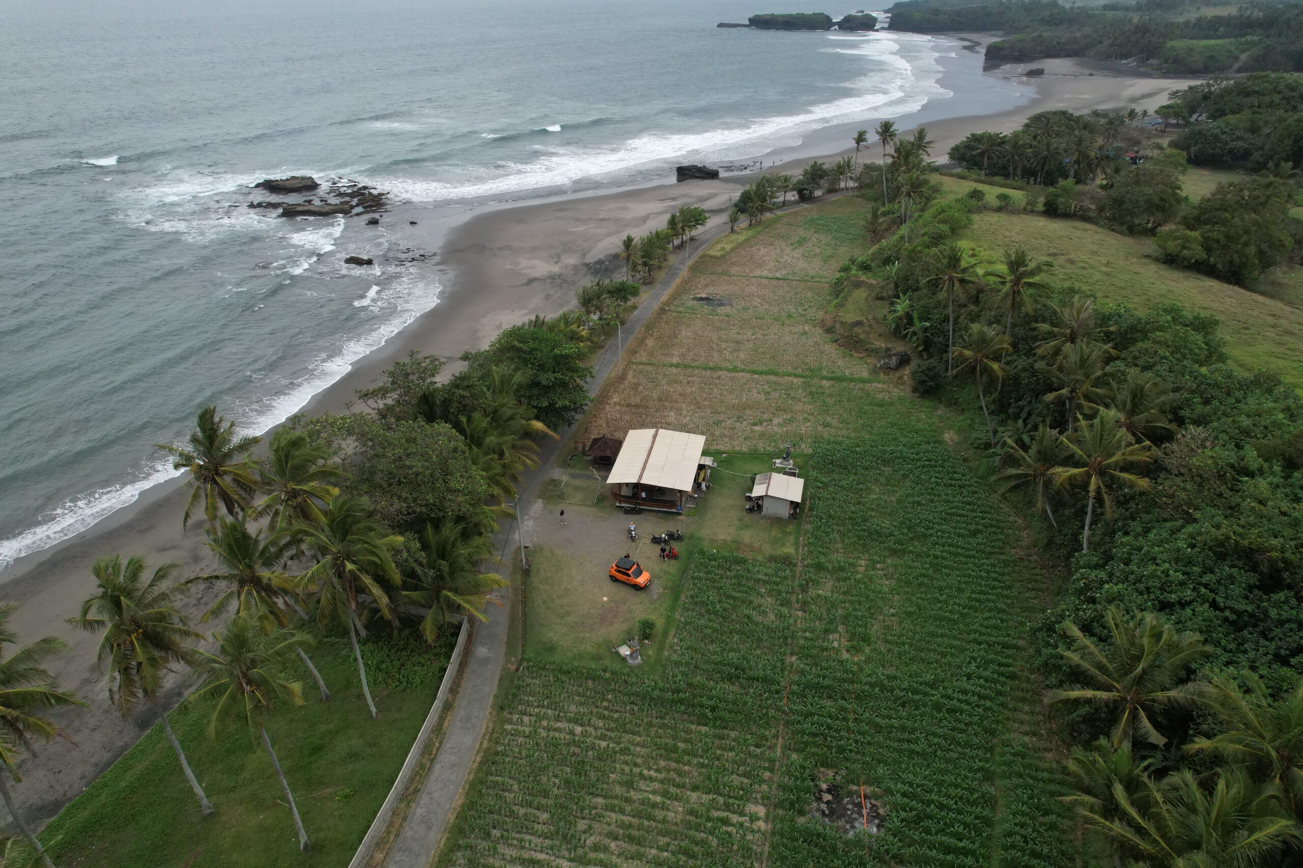 Aerial view of the camper on a coast road between fields and black sand
