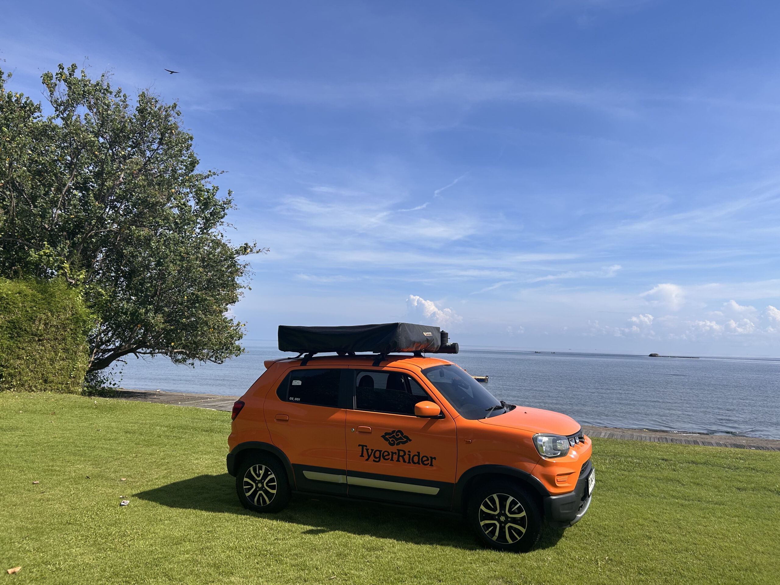 Camper parked on grass overlooking calm sea