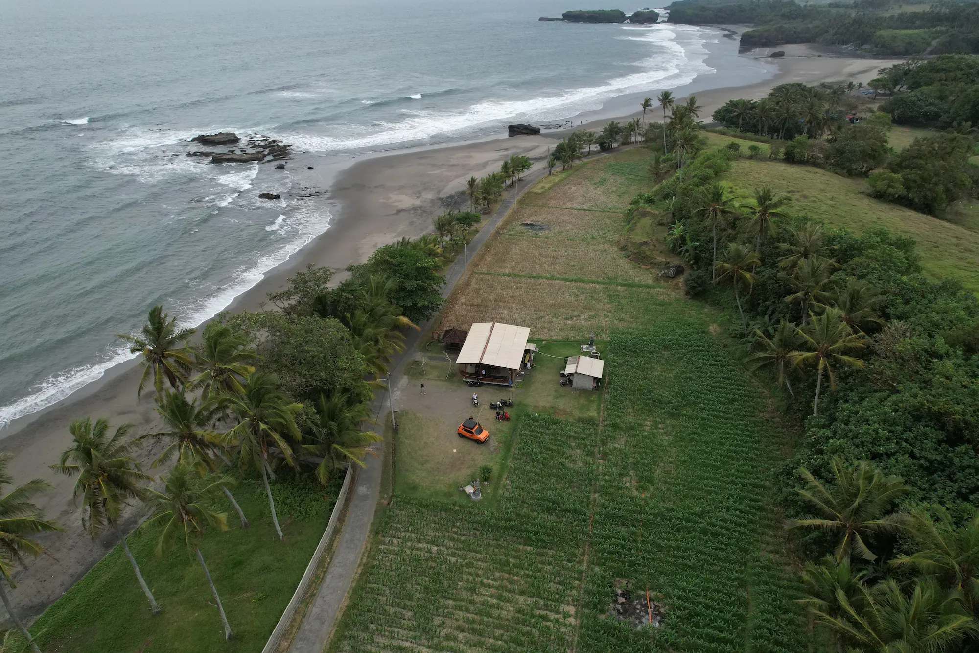 Aerial view of the camper between fields and black sand beach
